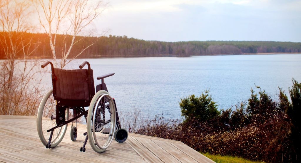 Illustrasjonsbilde erstatningsrett - Bilde av tom rullestol på en platting med utsikt over sjøen